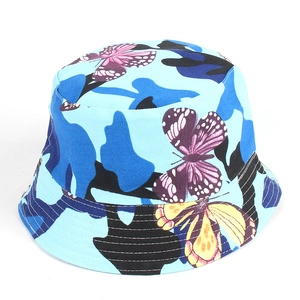 Dettaglio del cappello a secchiello con stampa mimetica blu e farfalle gialle vivaci