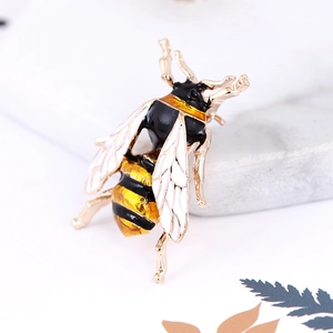Macro shot of 3D enamel honey bee brooch with crystals on white marble stone