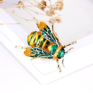 Macro shot of bee brooch with green enamel and sparkling rhinestones on gold base