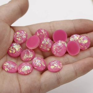 Close-up of 12mm pink synthetic opal resin cabochons with iridescent glitter flakes