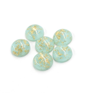 Macro detail of 12mm oval resin cabochons with gold foil flakes for jewelry making