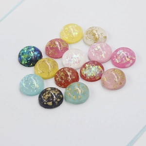 Macro view of 12mm oval synthetic opal resin cabochons with sparkling gold foil flakes