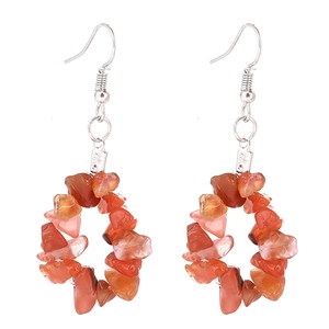 Détail des boucles d'oreilles créoles en éclats de pierres oranges et crochets
