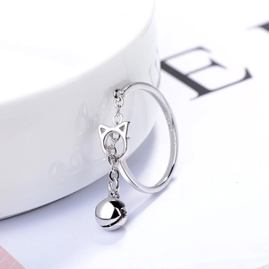 Anillo abierto de plata S925 con colgante de gato y cascabel sobre cerámica blanca
