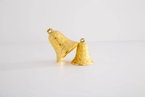 Detail of two gold Christmas bell ornaments in small and large sizes on white background
