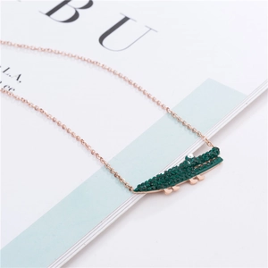 Détail du collier en or rose avec un pendentif crocodile en cristaux verts