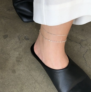 Close-up of a layered S925 sterling silver snake chain anklet worn on the ankle