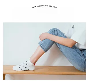 White ankle sock with blue stars and red heel tab shown on model sitting on a wooden bench