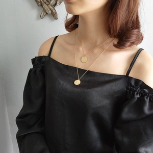 Close-up of a double layered gold coin pendant necklace worn by a female model