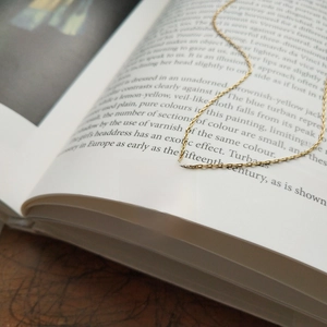 Macro view of gold coin pendant with LIVE TO EXPRESS engraving on an open book