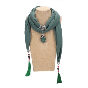 Detail of green ethnic scarf necklace with emerald gemstone pendant and beaded tassels