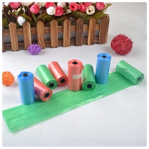 Three-color roll of portable pet waste bags with one green bag expanded on wooden fence