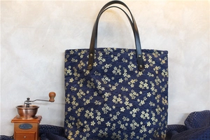 Détail du sac en toile bleu marine avec motifs de fleurs de cerisier et anse en cuir