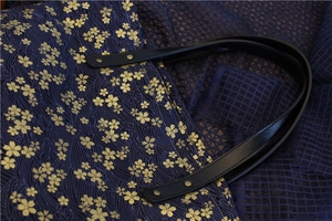 Détail du sac en toile bleu marine avec motifs cerisiers dorés et rivets en cuir