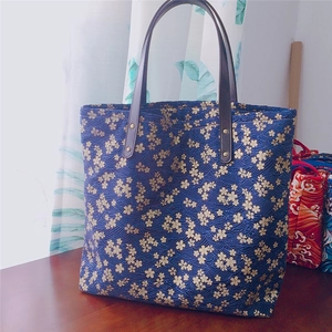Détail du sac fourre-tout en toile bleu marine avec motifs dorés de cerisiers et vagues