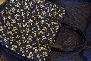 Détail du sac en toile bleu marine avec motifs de fleurs de cerisier et poignée en cuir
