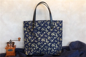 Détail du sac cabas en toile bleu marine avec motifs cerisiers dorés et anses en cuir