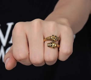 Detailed close-up of a vintage gold skull open ring with scale texture on model's hand