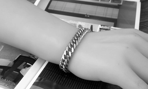 Close-up of chunky stainless steel Cuban link bracelet worn on a wrist in a fashion style