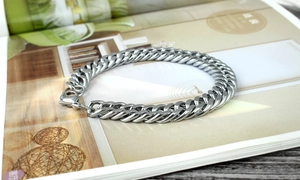 Close-up of a heavy silver Cuban link bracelet on a magazine for a luxury lifestyle look