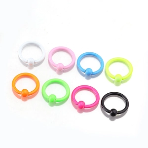 Detailed view of eight colorful neon coated stainless steel BCR rings for body piercing