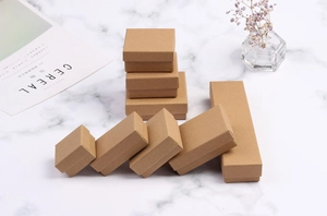 Various sizes of vintage kraft paper jewelry boxes on white marble with dried flowers