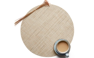Macro shot of circular PVC table mat with beige bamboo texture weave on white background