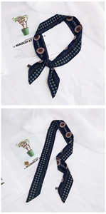 Detail showing tied navy blue skinny silk scarf with white floral patterns and red flowers