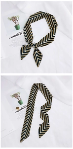 Detail of long narrow silk scarf with black white and gold chevron pattern texture