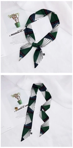 Detail of green geometric silk scarf tied on a white fabric and magazine background