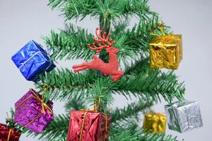 Close-up of a red glitter reindeer and colorful gift box ornaments on Christmas tree