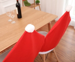 Detail of red Santa hat chair covers with white pom-poms on a festive wooden table