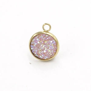 Macro view of a 10mm round pink glitter pendant with polished golden stainless steel frame