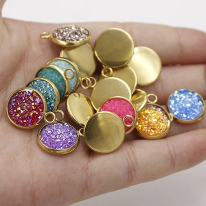 Handheld view of assorted colorful resin and gold stainless steel round charms for DIY jewelry
