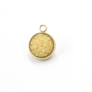 Detail of round gold stainless steel charm with beige crystal inlay for jewelry making