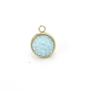 Macro detail of round light blue resin pendant with gold stainless steel frame