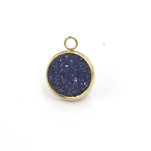 Detailed view of round gold stainless steel charm with deep blue glitter resin inlay