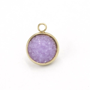 Macro shot of circular gold stainless steel pendant with purple resin crystal inlay
