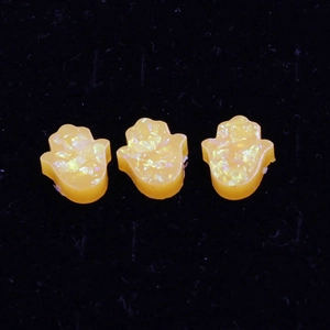Macro shot of three synthetic orange opal Hamsa hand charms for DIY jewelry making