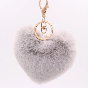 Macro detail of a plush grey heart-shaped faux fur keychain with a golden metal clasp