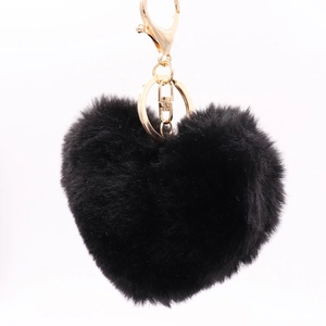 Close-up of black plush heart keychain with gold metal clasp on a plain white background