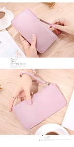Pink PU leather long wallet with wrist strap and dual-layer storage on wooden table