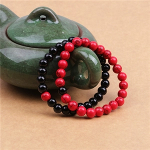 Dettaglio di braccialetti con perline di turchese rosso e nero su una teiera in ceramica
