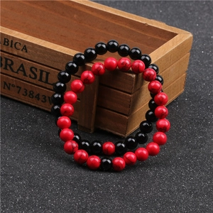 Dettaglio di braccialetti con perline di turchese rosso e nero da 8mm su vassoio in legno