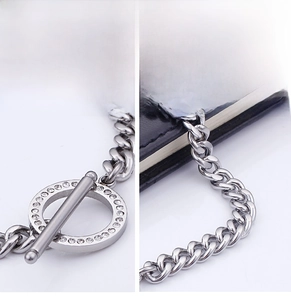 Dettaglio macro del bracciale a catena cubana in acciaio con chiusura a T e strass