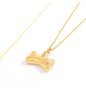 Close-up of golden dog bone cremation pendant necklace for ashes with polished finish