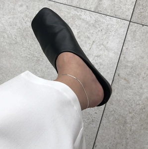 Close-up of minimalist S925 sterling silver blade chain anklet worn with black mules