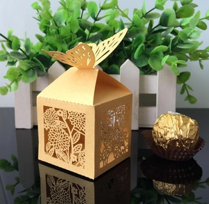 Close-up of laser-cut ivory butterfly wedding favor box with gold hollow pattern