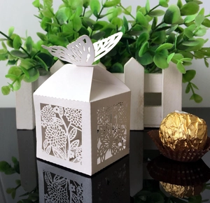 Detail view of laser-cut ivory butterfly wedding favor box with intricate hollow patterns