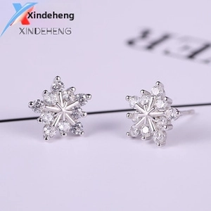 Macro shot of silver snowflake stud earrings featuring intricate pavé-set zircons details